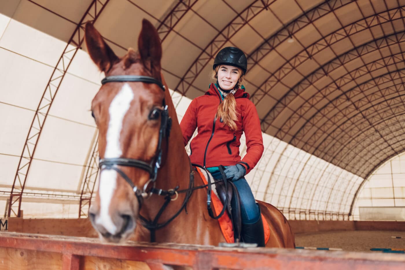 serious woman riding a horse in the arena for equestrian sport